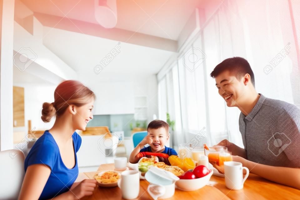 glückliche junge Familie gesundes Frühstück in der Küche mit roten Details auf hellen Morgenlicht
