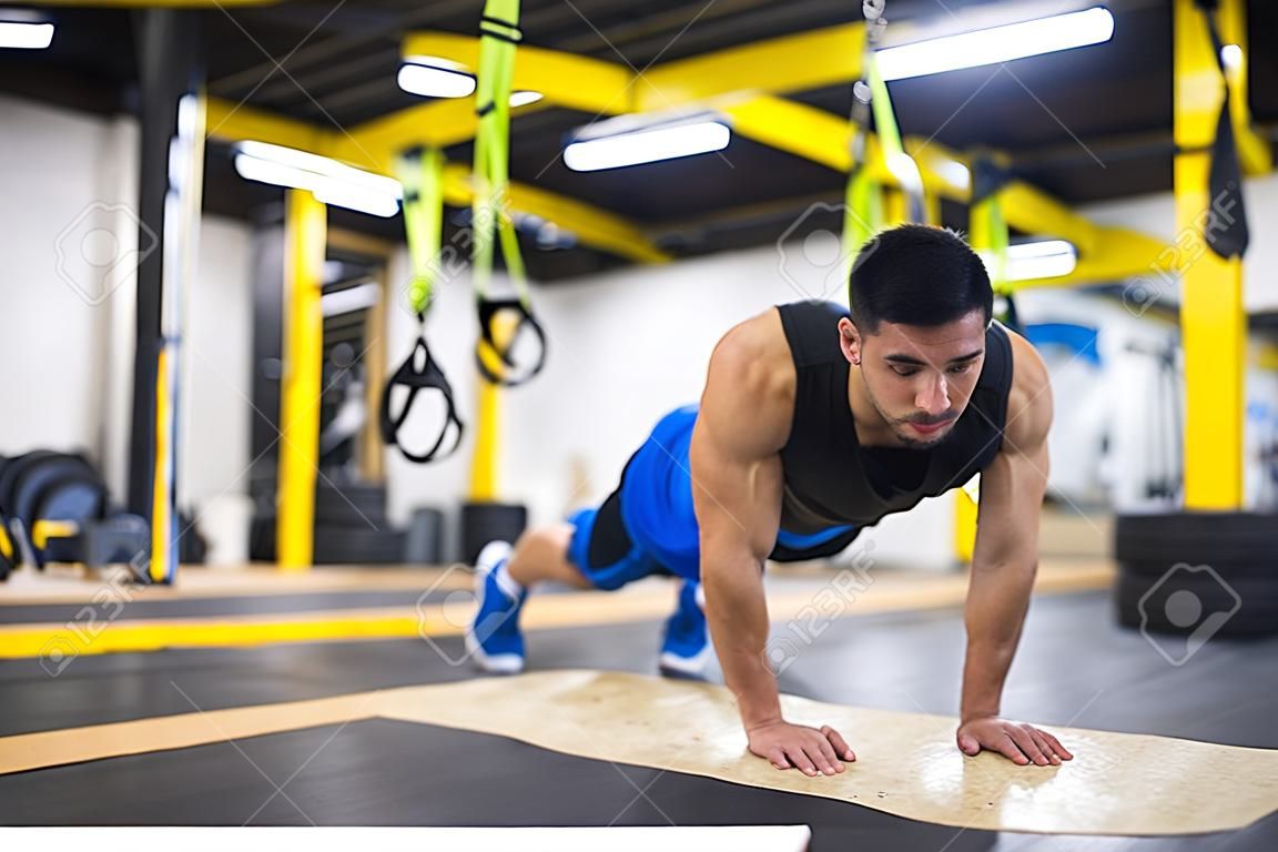 Young strong man doing pushups  at cross fitness gym