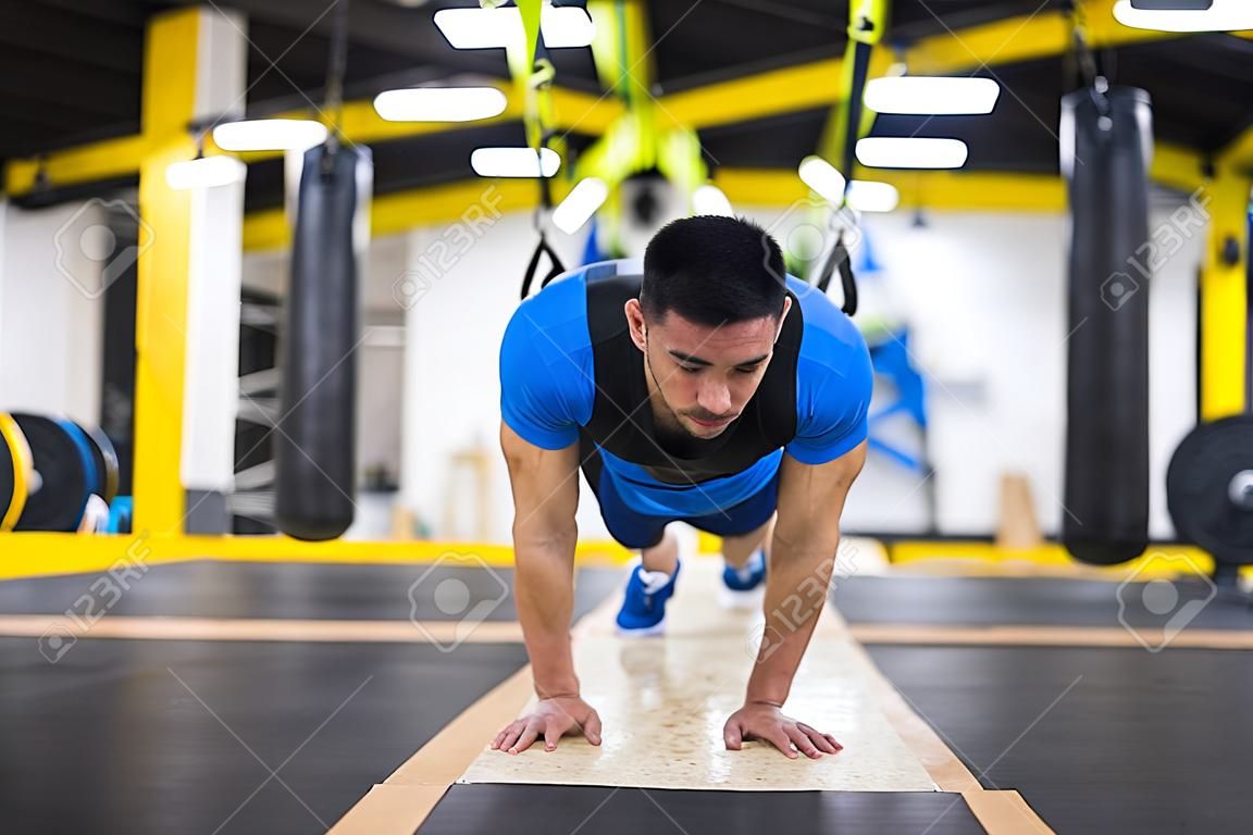 Jovem homem forte fazendo flexões no cross fitness gym