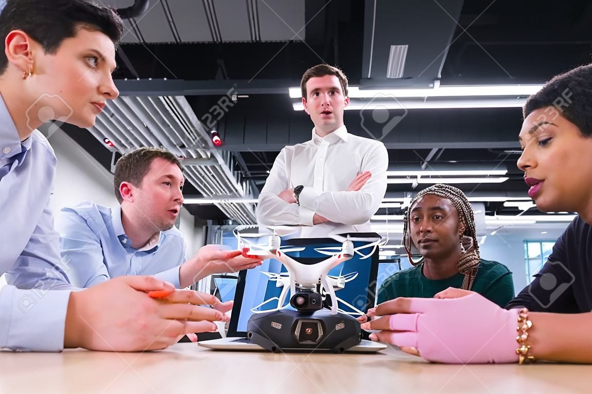 multietnisch startup business team bespreken nieuwe business plan, werken op laptop en tablet computer terwijl leren over drone technologie voor nieuwe business progress