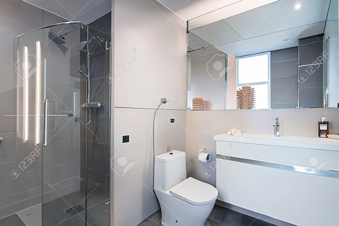 luksusowe stylowe wnętrze łazienki z toaletą, umywalką bidetową i przestronną szklaną kabiną prysznicową fantazyjny prysznic na ścianie