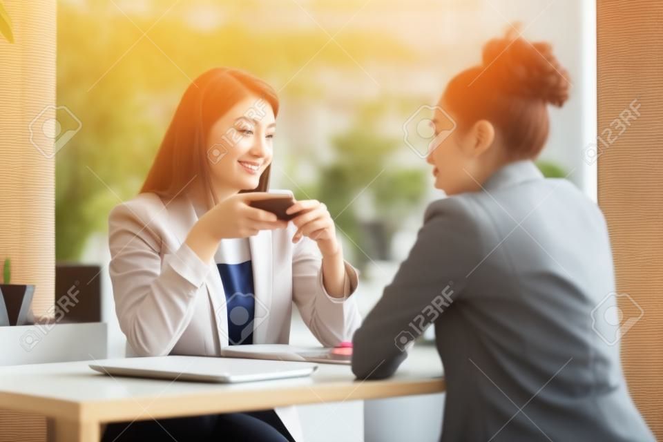 Dos jóvenes mujeres de negocios sentadas a la mesa en el café. Chica usando laptop, smartphone, blogs. Trabajo en equipo, reunión de negocios. Trabajadores autónomos...