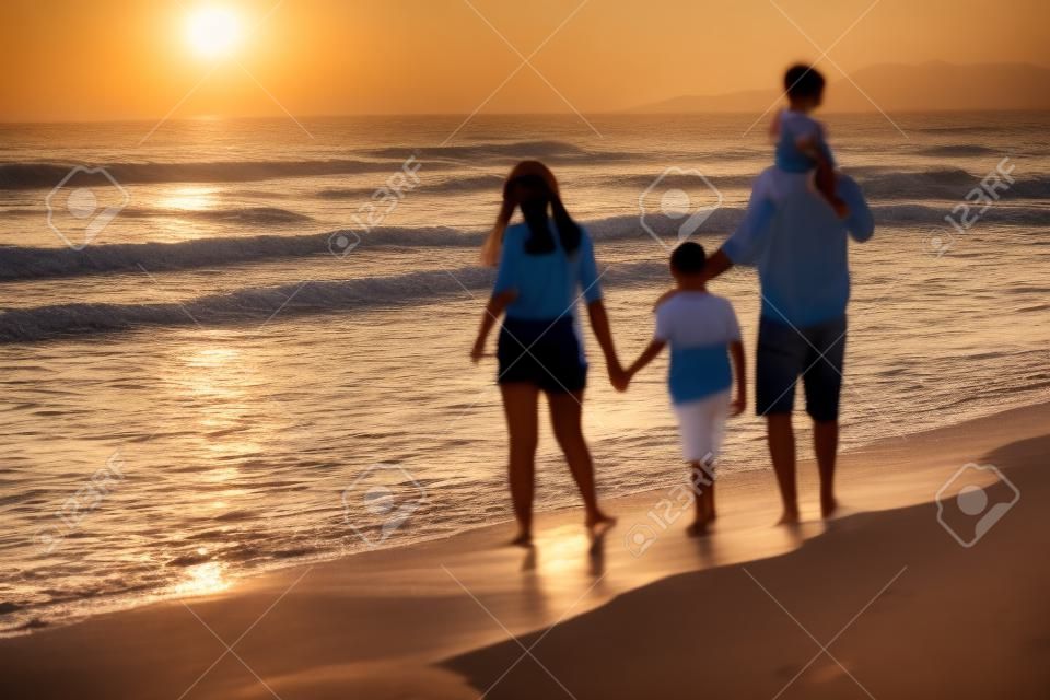 Riunioni di famiglia e socializzazione sulla spiaggia al tramonto. la famiglia cammina lungo la spiaggia sabbiosa. fuoco selettivo