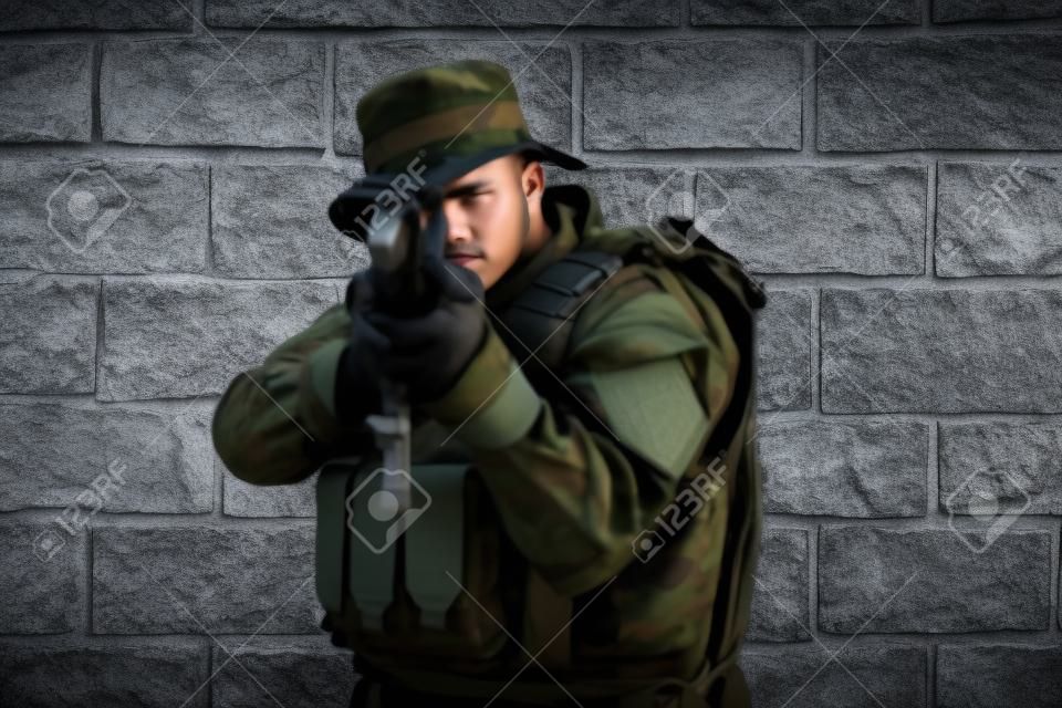 Un soldado en uniforme se para frente a un muro de piedra con equipo de guerra completo preparándose para la batalla