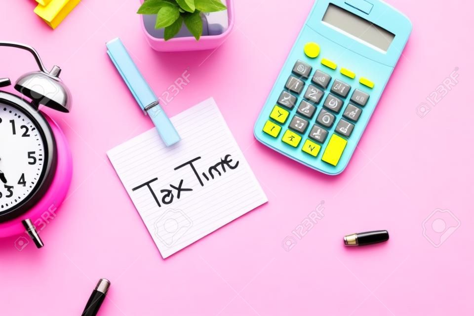 belastingtijd concept op plakkerige noot, rekenmachine en klok op roze achtergrond