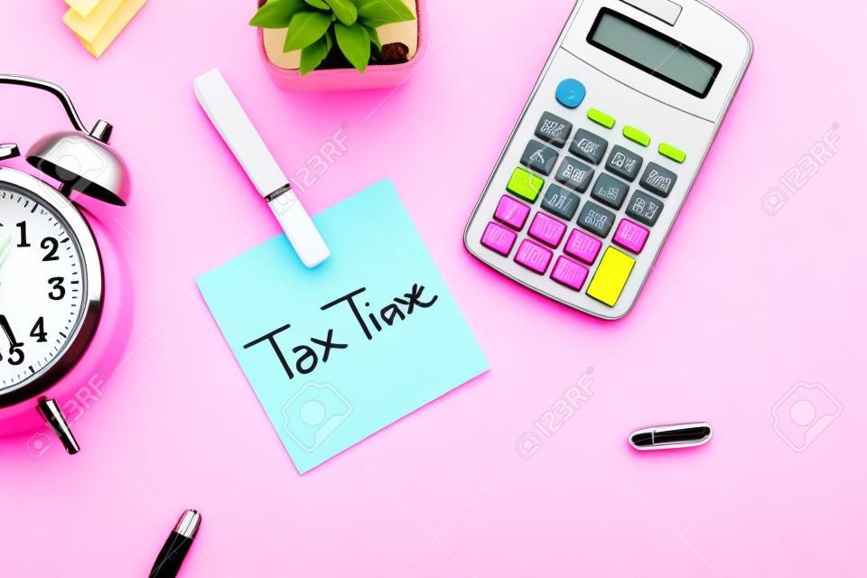 belastingtijd concept op plakkerige noot, rekenmachine en klok op roze achtergrond