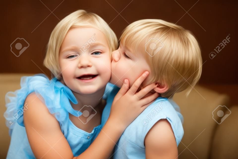 Мальчик целует свою старшую сестру в щеку
