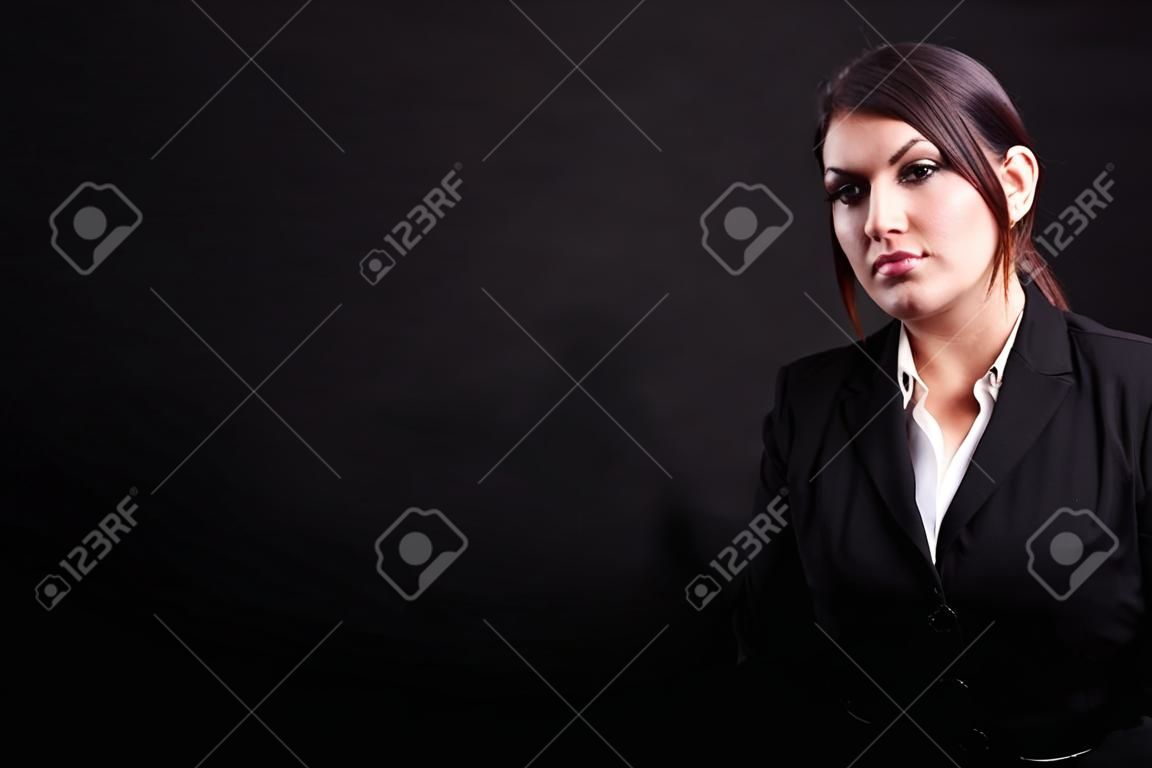 Businesswoman in suit in studio photo over black background
