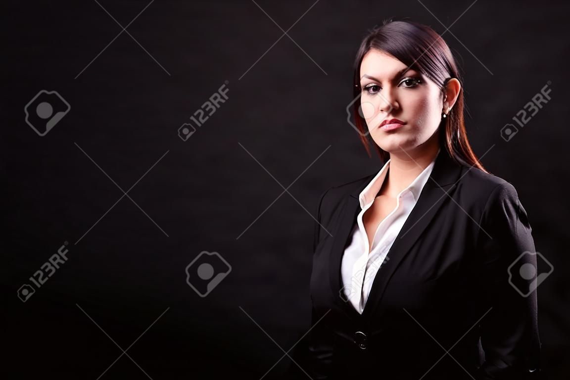 Businesswoman in suit in studio photo over black background