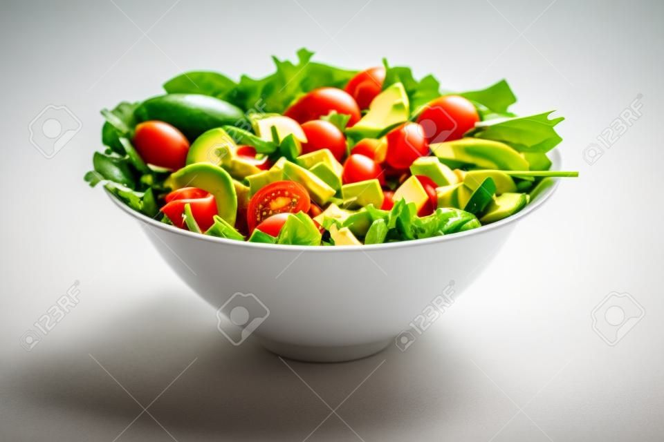 Salade verte à l'avocat, à la tomate et aux légumes frais isolés sur fond blanc