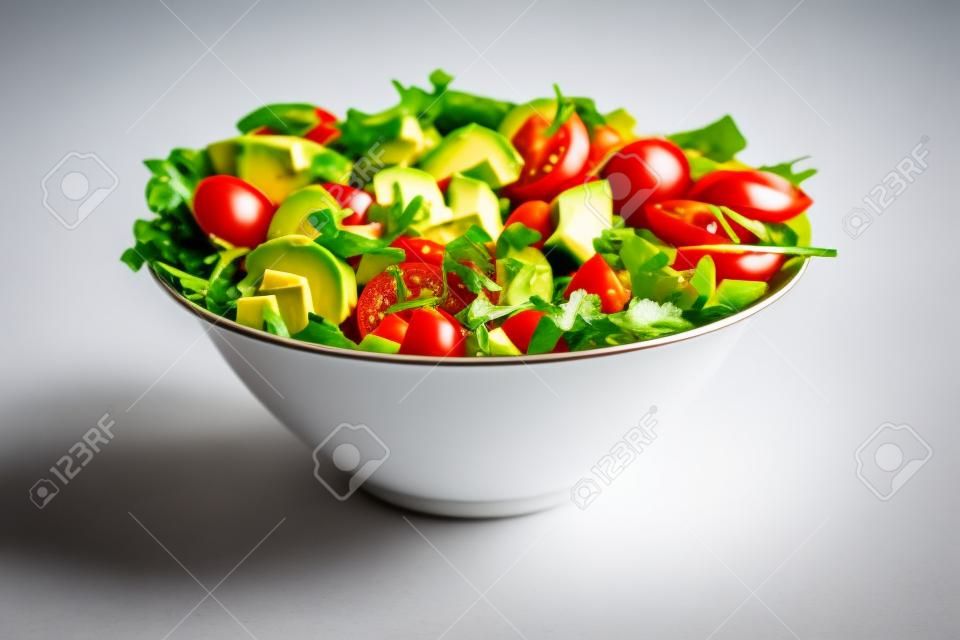 Ensalada verde con aguacate, tomate y verduras frescas aislado sobre fondo blanco.