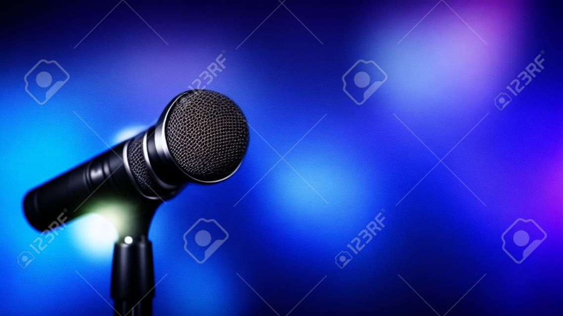 Öffentliche sprechende Hintergründe, Nahaufnahme des Mikrofons auf dem Ständer für die Bühnenperformance der Sprecherrede mit unscharfem und Bokeh-hellem Hintergrund.