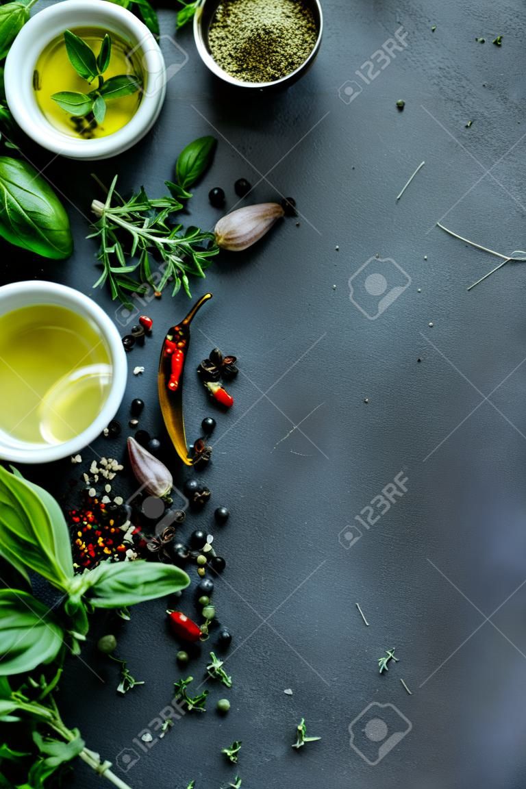 Mix of fresh Italian herbs from garden. Basil, chili, oregano, black pepper. Olive oil: Dark background. Copy space.