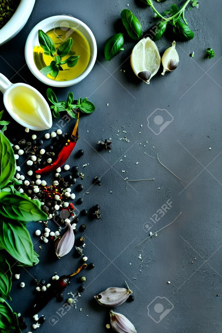 Mix van verse Italiaanse kruiden uit de tuin. Basil, chili, oregano, zwarte peper. Olijfolie: donkere achtergrond. Kopieer ruimte.