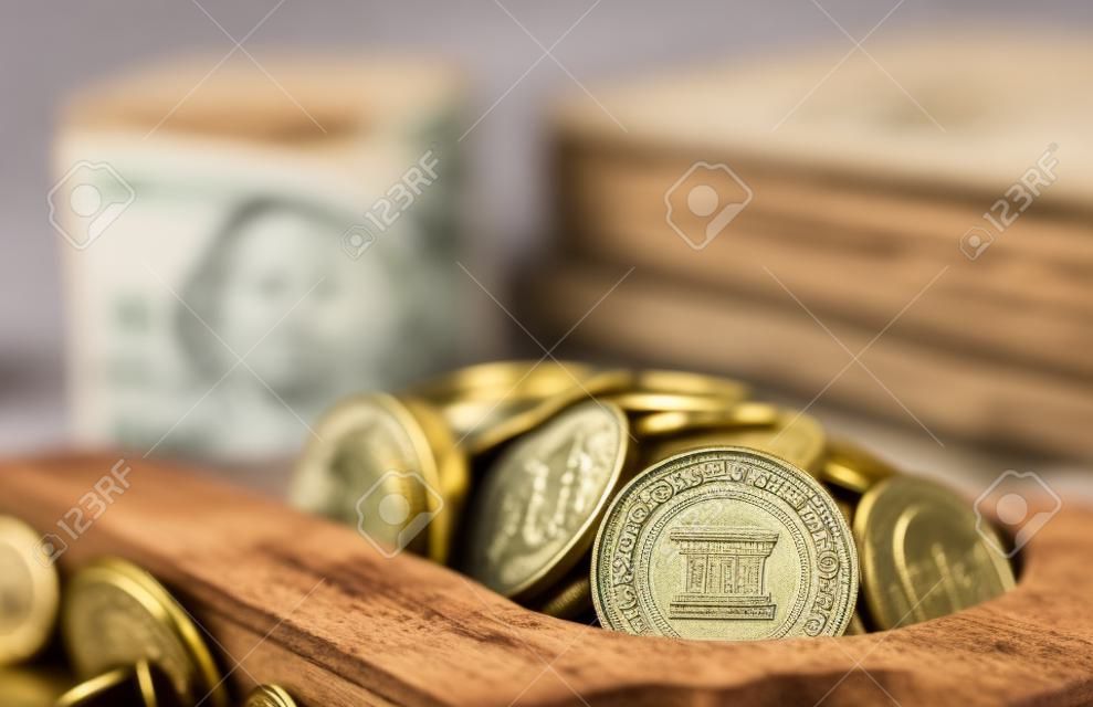 Vintage wooden box full of money: rolled up Polish zloty banknotes and coins from above on wooden surface. Concept of personal savings kept in cash at home and collecting for retirement