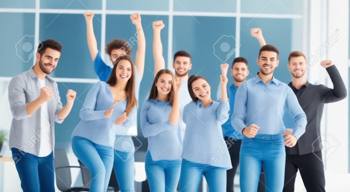 Equipo de jóvenes felices parados en una nueva oficina