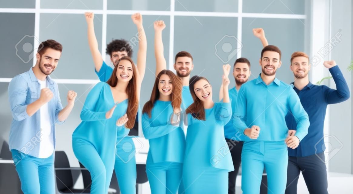 Team di giovani felici in piedi in un nuovo ufficio