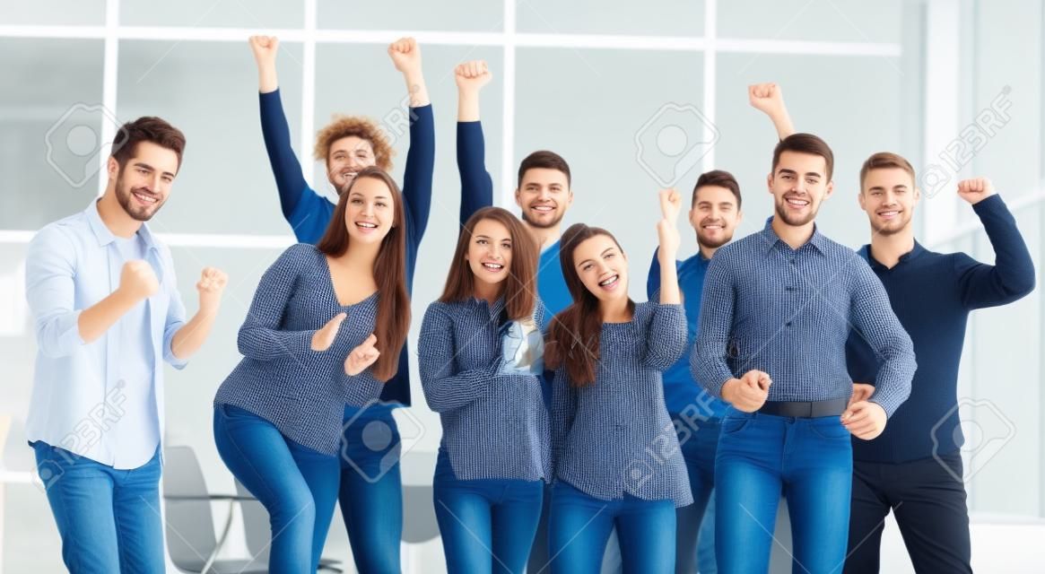 Zespół szczęśliwych młodych ludzi stojących w nowym biurze