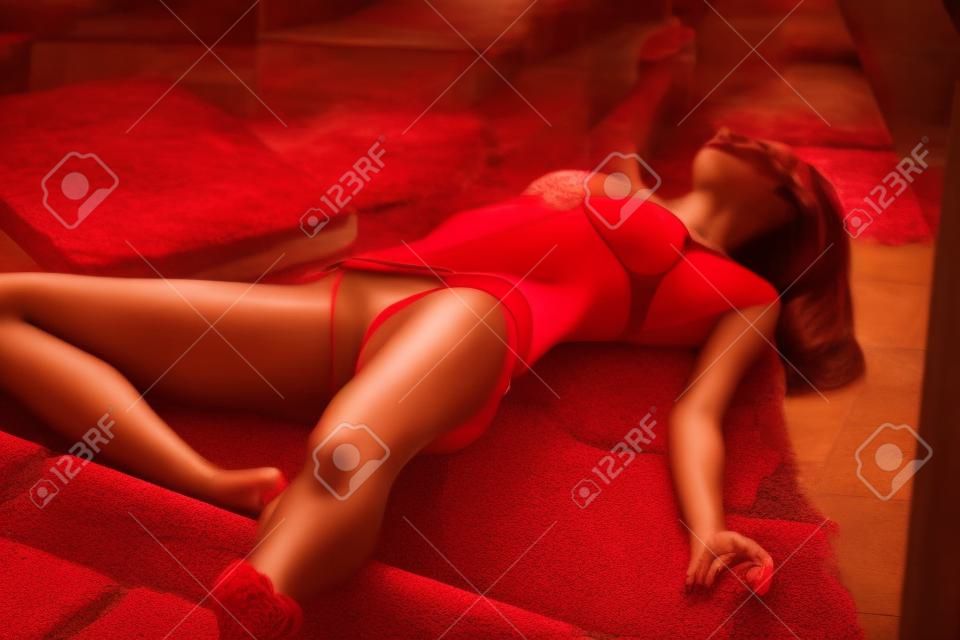 hermosa mujer jugando muerto, tirado en las escaleras en bikinis rojos
