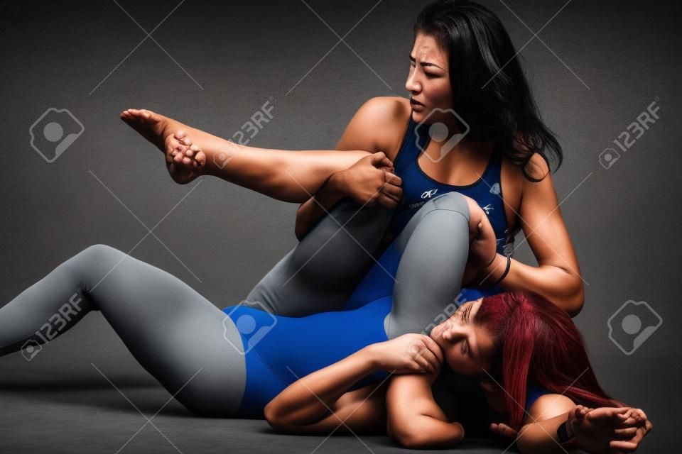 zwei Frauen kämpfen mit Ringen hält über grauem Hintergrund