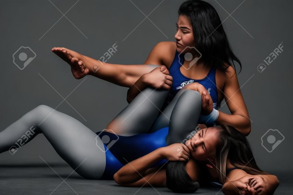 due donne che combattono con il wrestling tiene su sfondo grigio