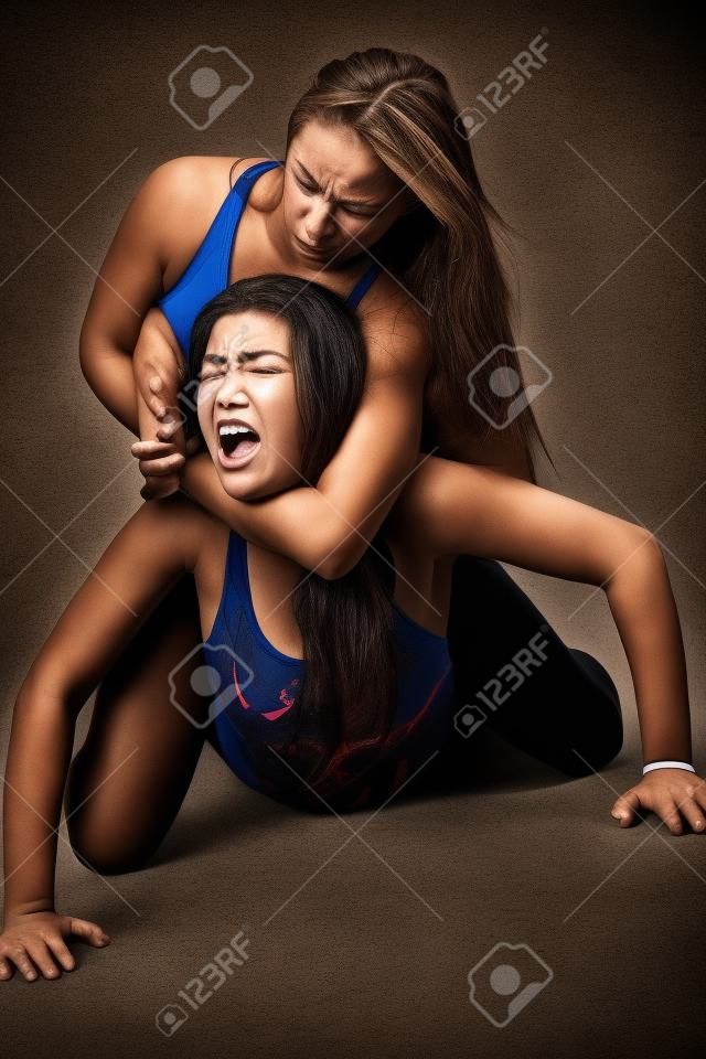 two women fighting - wrestling choke hold on the ground