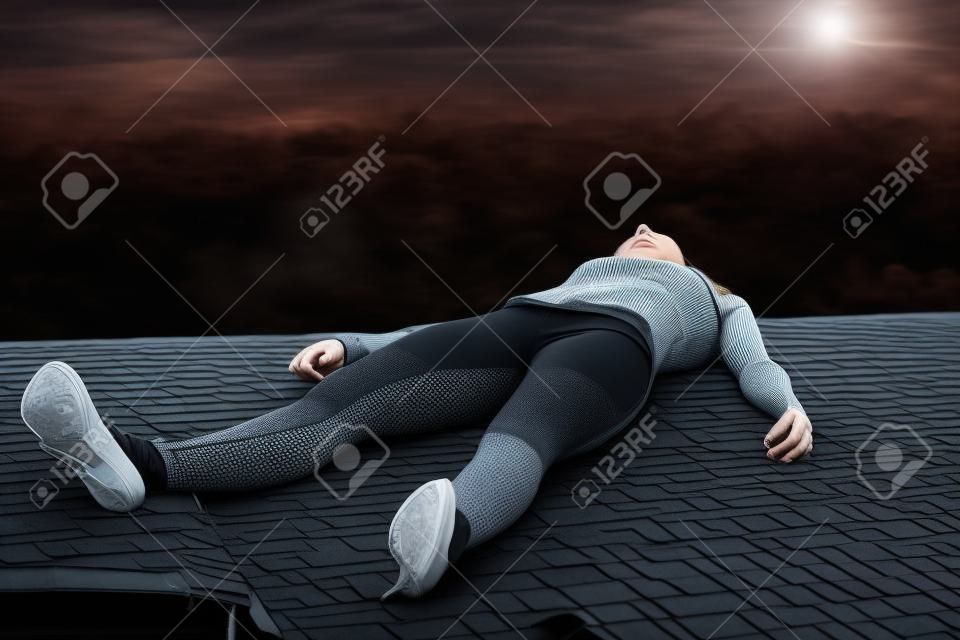 犯罪シーン - 黒のレギンス不動は家の屋根の上に横たわる若い女性