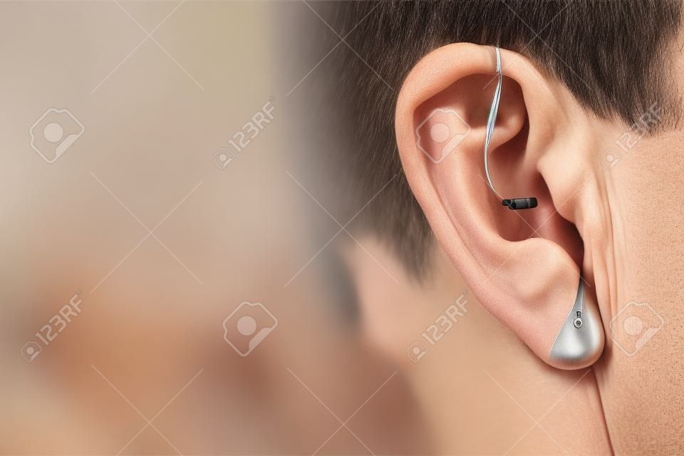 Nowoczesny cyfrowy aparat słuchowy dla osób głuchoniemych i niedosłyszących w uchu starszego mężczyzny.