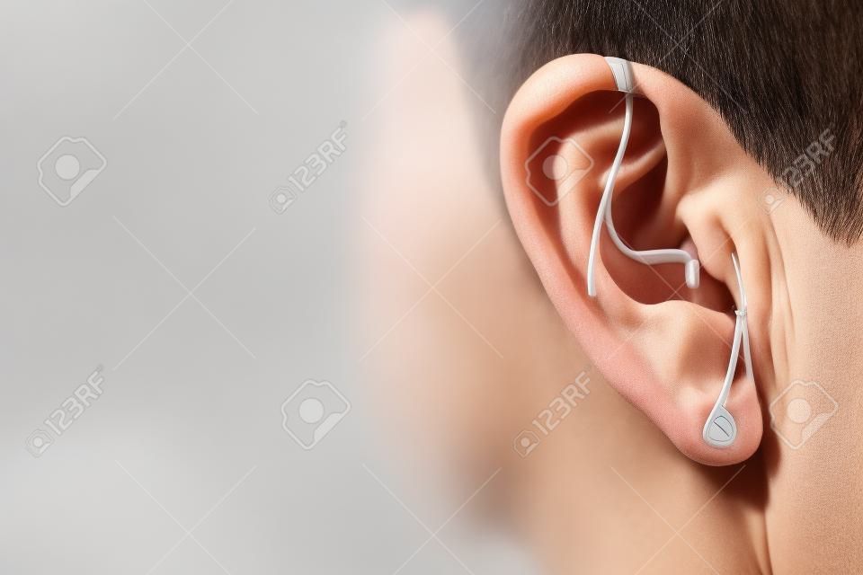 Nowoczesny cyfrowy aparat słuchowy dla osób głuchoniemych i niedosłyszących w uchu starszego mężczyzny.