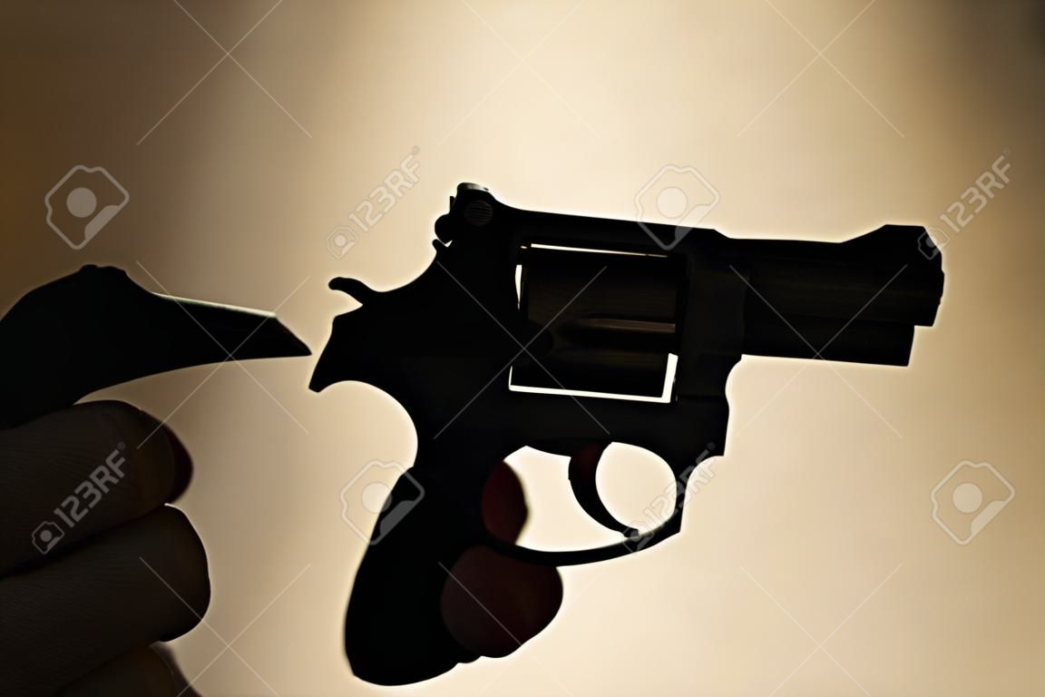 Pistol automatic handgun weapon in silhouette in hand of killer atmospheric dark dramatic photo.