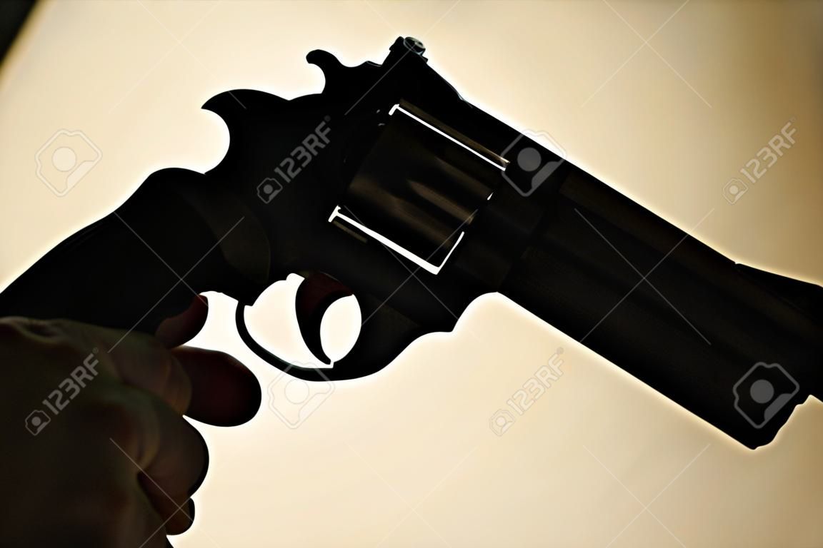Pistole automatische Handfeuerwaffe in Silhouette in der Hand eines mörderischen atmosphärischen dunklen dramatischen Fotos.