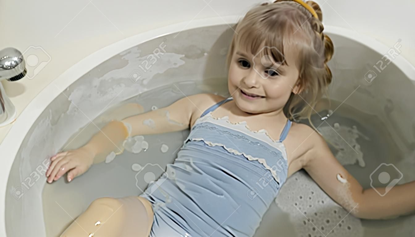 Attraente ragazza di quattro anni fa il bagno in costume da bagno. Igiene per bambino biondo carino. Ragazza carina sorridente. Bambino grazioso, ragazza bionda di 4-5 anni in bagno