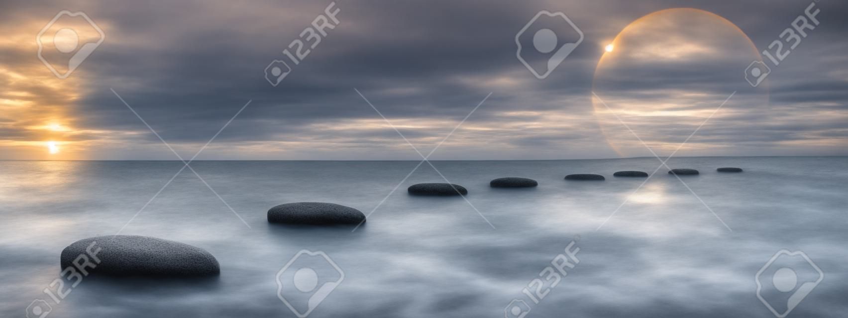 Grey stones steps upon the ocean going to the sun by sunset