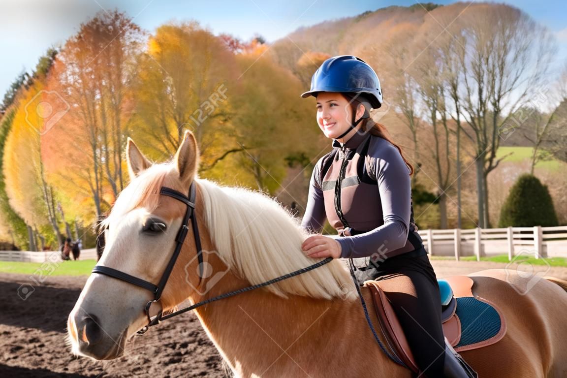 在阳光明媚的秋日户外骑马的少女画像
