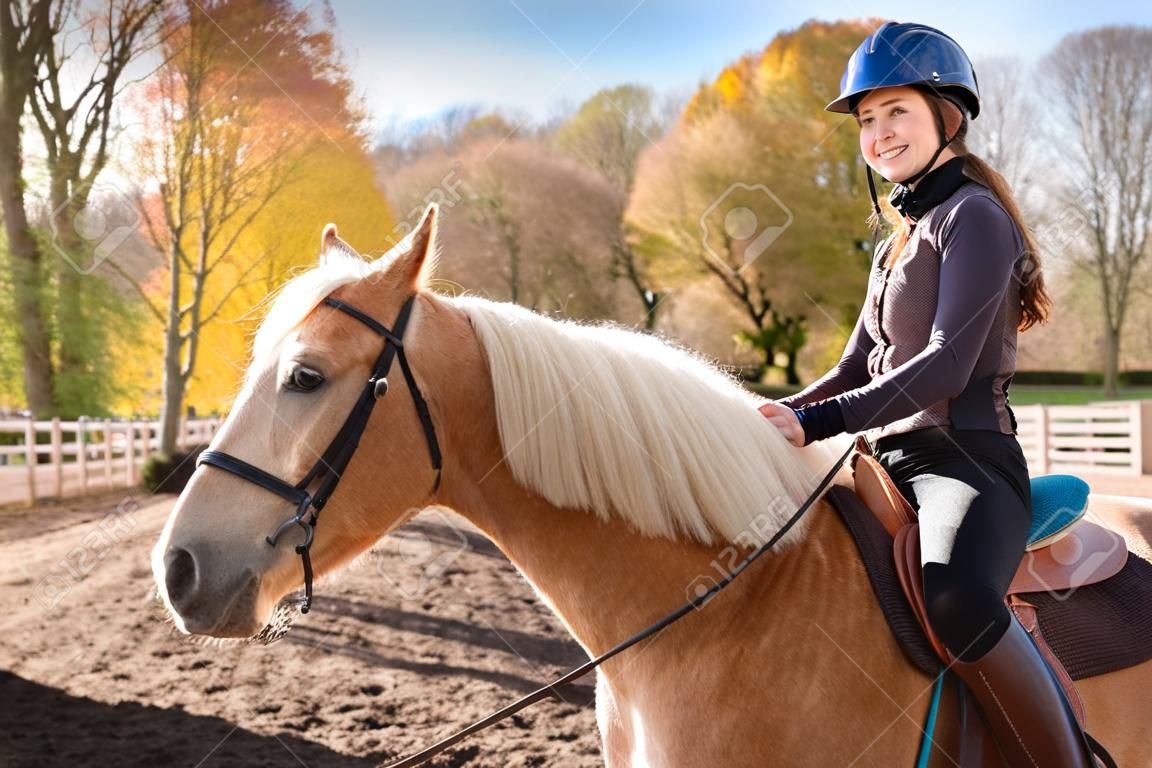 在阳光明媚的秋日户外骑马的少女画像