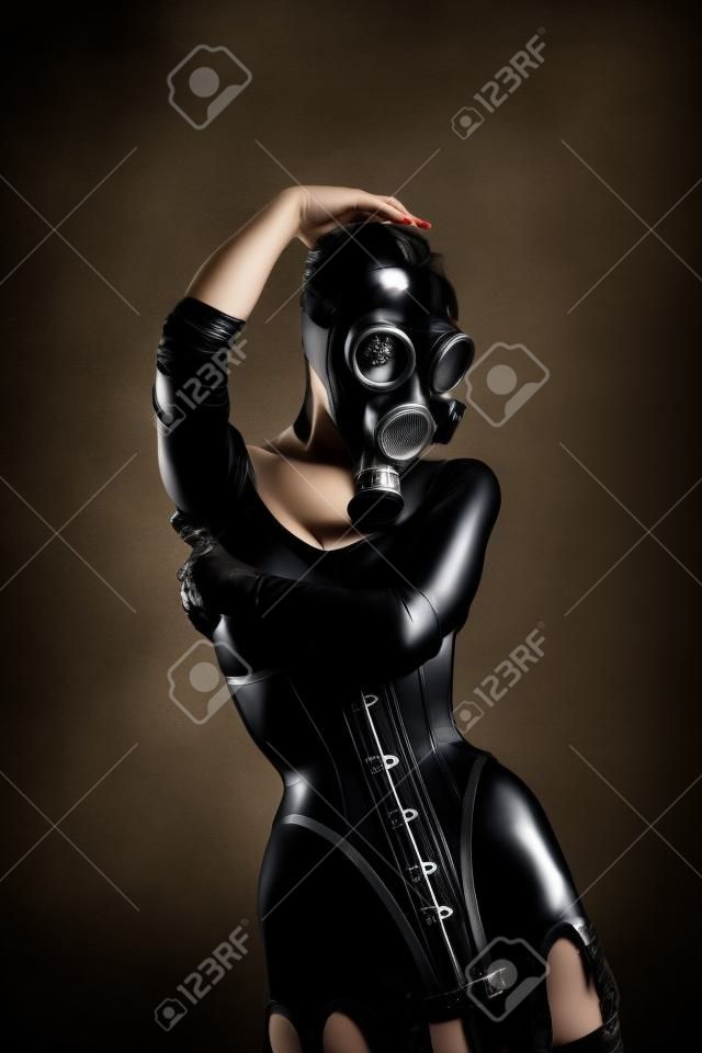 Woman in latex corset and gas mask, studio shot on black background 