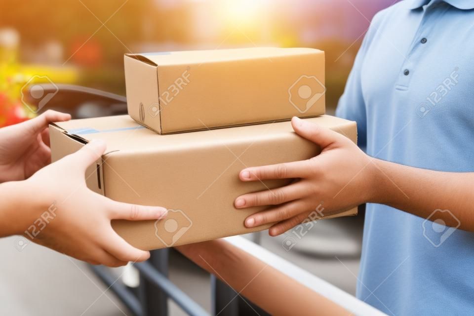 Lieferpostmann, der dem Empfänger Paketkasten gibt, junger Besitzer, der Kartonpakete aus dem Postversand akzeptiert, Heimkurier und Lieferservice-Gedankenkonzept.