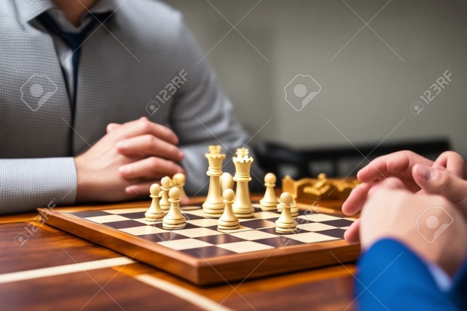 Intelligent businessman playing chess game competition with the opposite team, planning business strategic to development for win and success, Gold and silver chess with player.