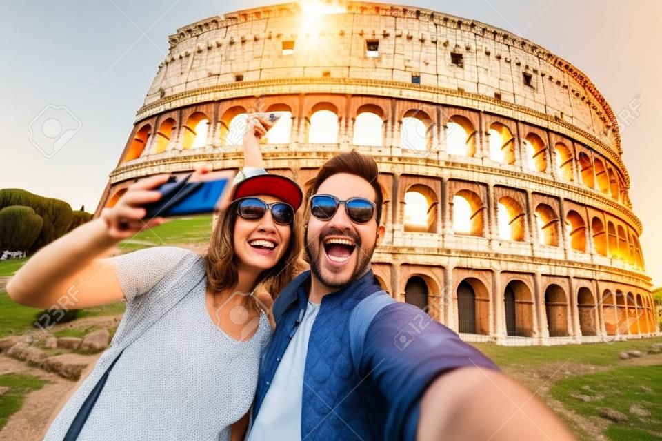 Glückliches Paar von Touristen, die im Kolosseum in Rom lächeln und ein Selfie machen.