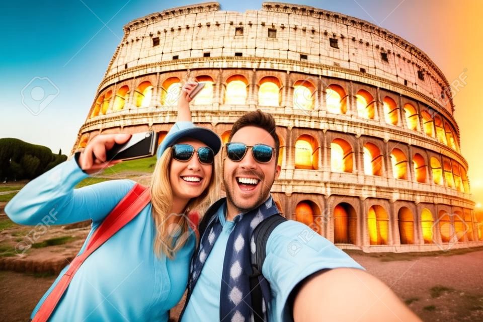 Szczęśliwa para turysta uśmiecha się i robi selfie w Koloseum w Rzymie.