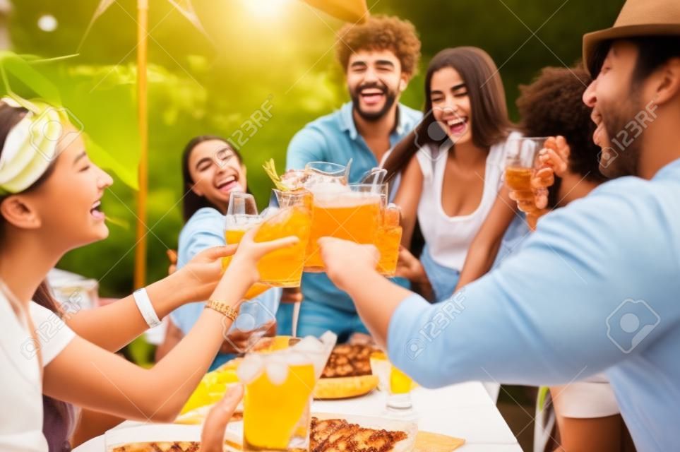 Young multiracial friends toasting beer at barbecue garden party - Young cheerful people cheering with cocktails on summer time