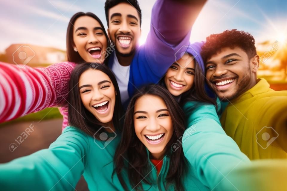 Grupo multicultural de amigos tomando fotos selfie afuera