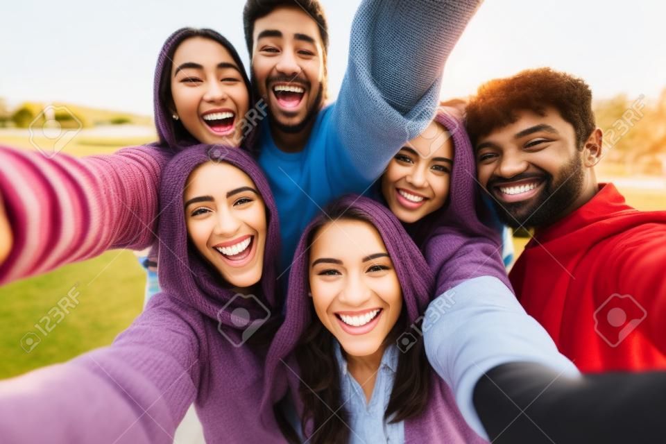 Grupo multicultural de amigos tomando fotos selfie afuera