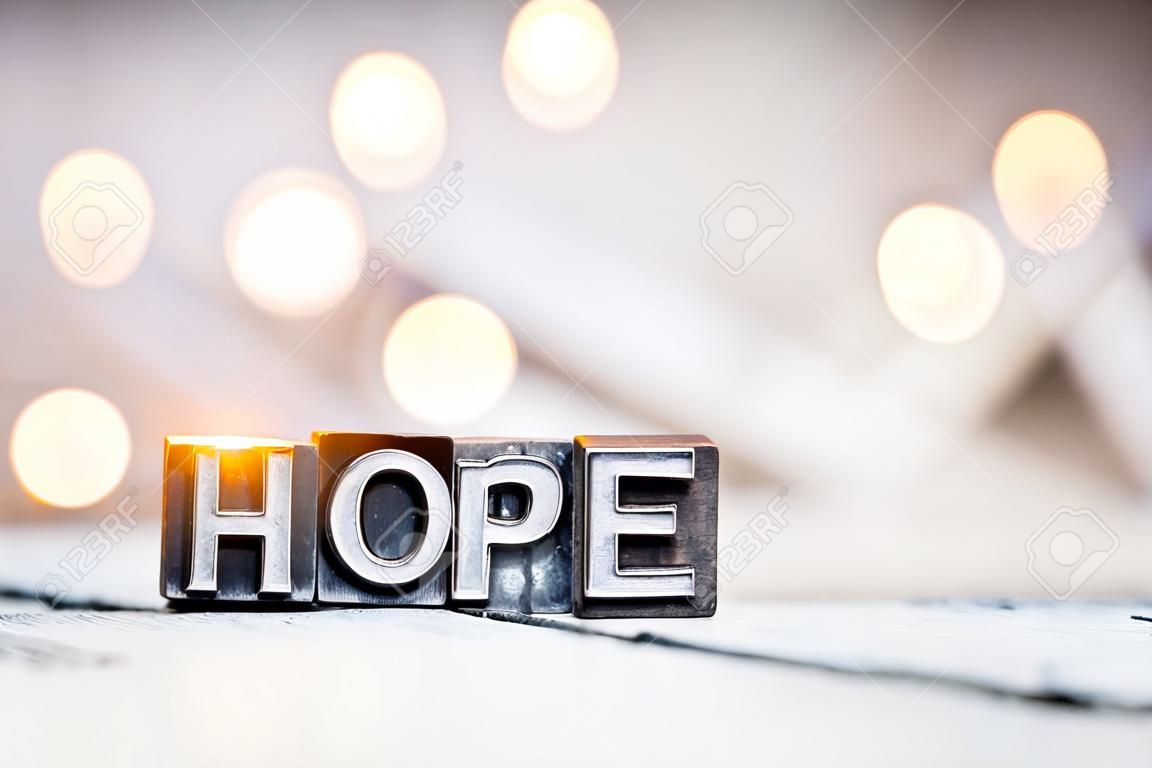 The word HOPE written in vintage metal letterpress type on a bokeh light and wooden background.
