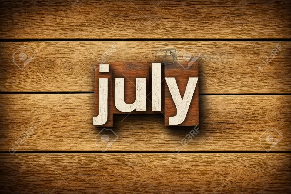 The word "JULY" written in vintage wood letterpress type on a vintage rustic background.