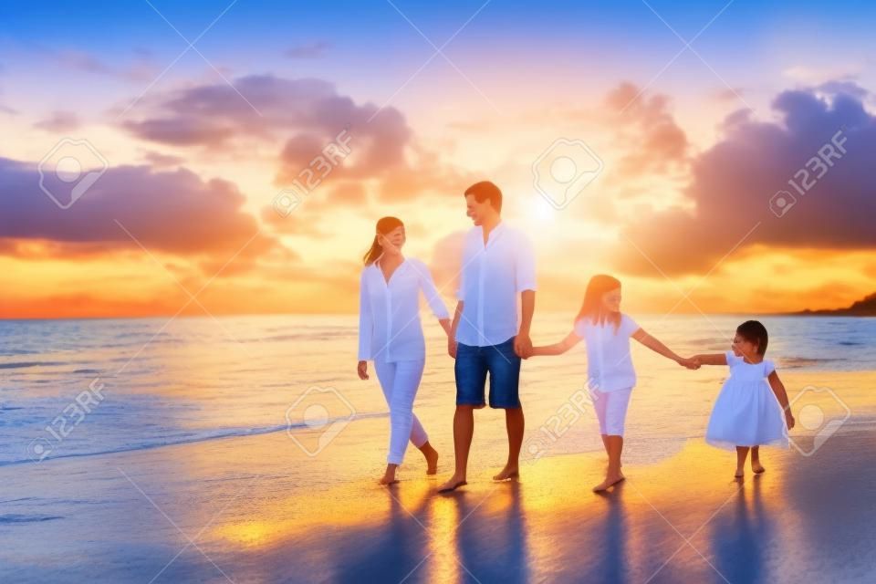 快樂的年輕家庭有樂趣走在海灘的日落