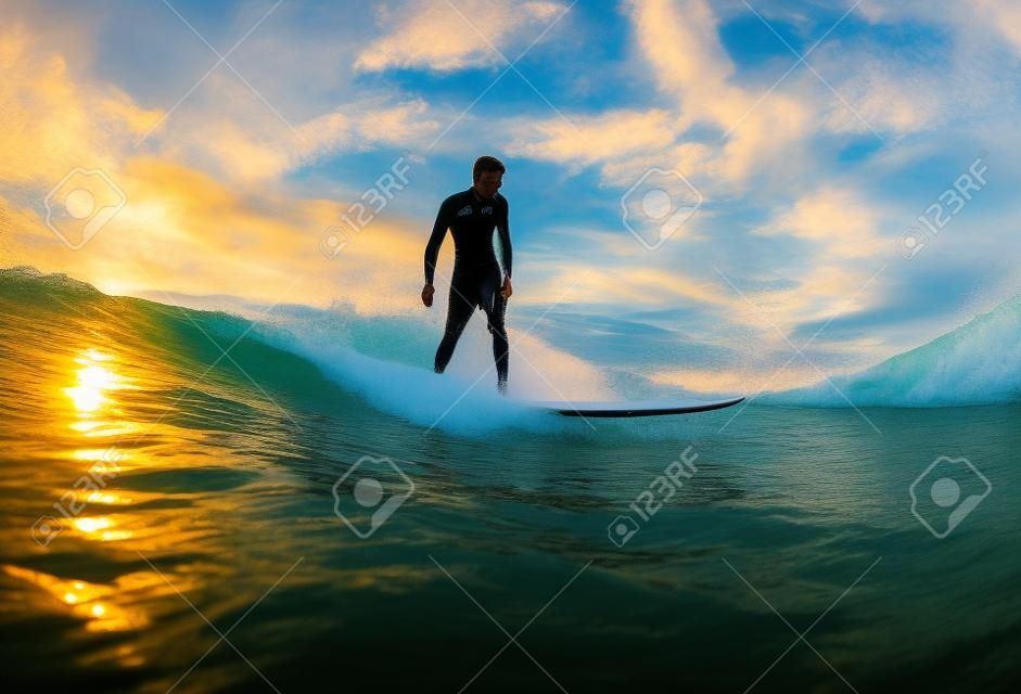 衝浪在日落。年輕男子騎波在日落。室外積極的生活方式。