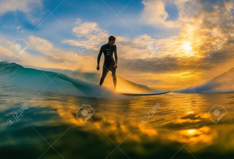 Surf al tramonto. Giovane uomo guida d'onda al tramonto. Outdoor Lifestyle attivo.