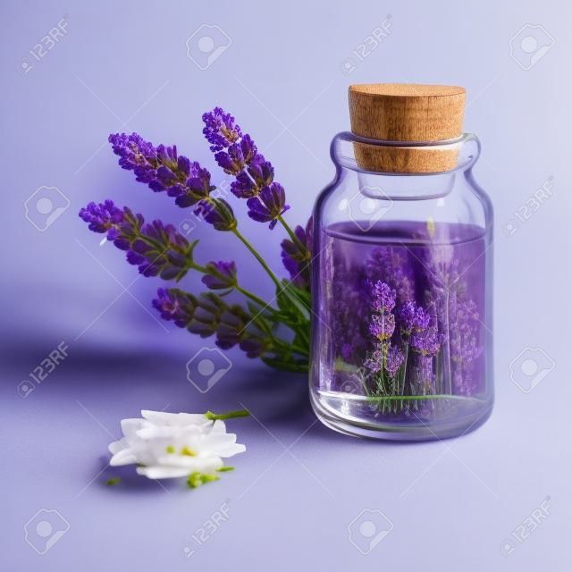 Lavander essential oil bottle and bunch of flowers.