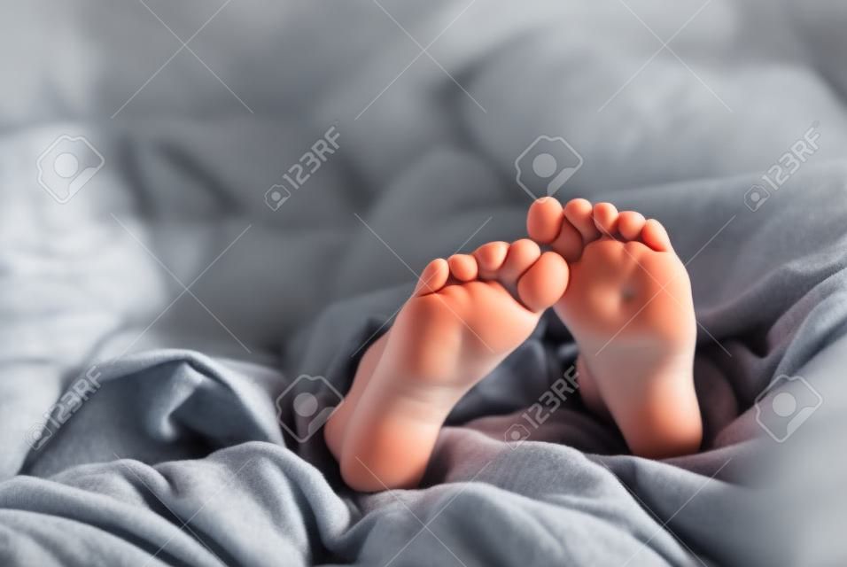 Niña durmiendo con los pies metiendo de mantas